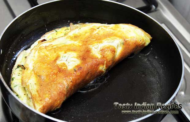When the omelette is done from down side, spread good amount of cheese over it and fold it