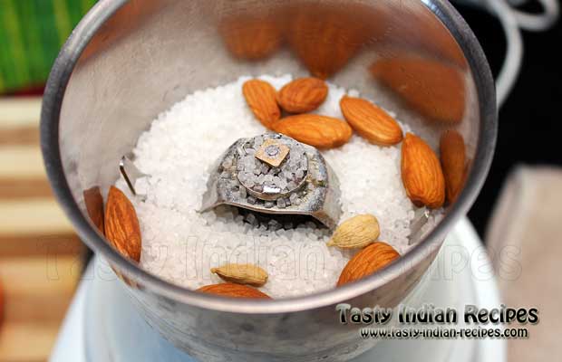 Put sugar, almonds and green cardamom in mixer grinder Put sugar, almonds and green cardamom in mixer grinder